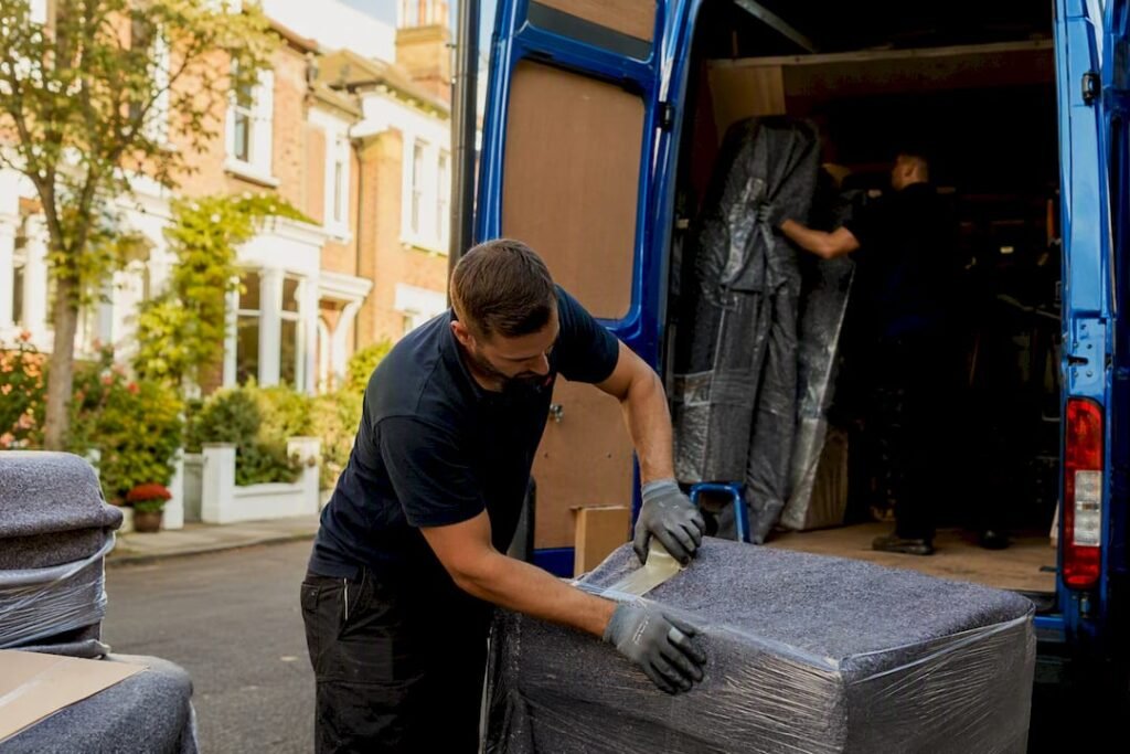 Movers wrapping furniture and loading van