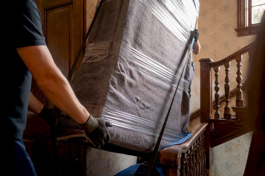 Movers lifting heavy bulky item on stairs